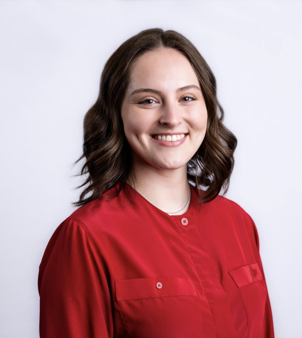 Professional headshot of a female with brown hair wearing a red shirt smiling at the camera.