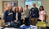 Students stand around table