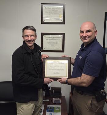 two men posing with a framed award