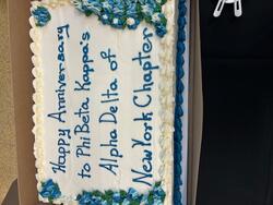 A decorated cake reading "Happy Anniversary to Phi Beta Kappa's Alpha Delta of New York Chapter"