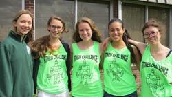 5 Geneseo students standing close, with the one on the far left wearing a green hoodie and the other four wearing neon green tank tops that say Fitness Challenge